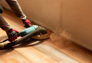 Workers are polishing the wooden floor, causing wood dust to spread everywhere