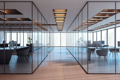 Contemporary empty office interior with glass partitions, stylish furniture and city view in background.