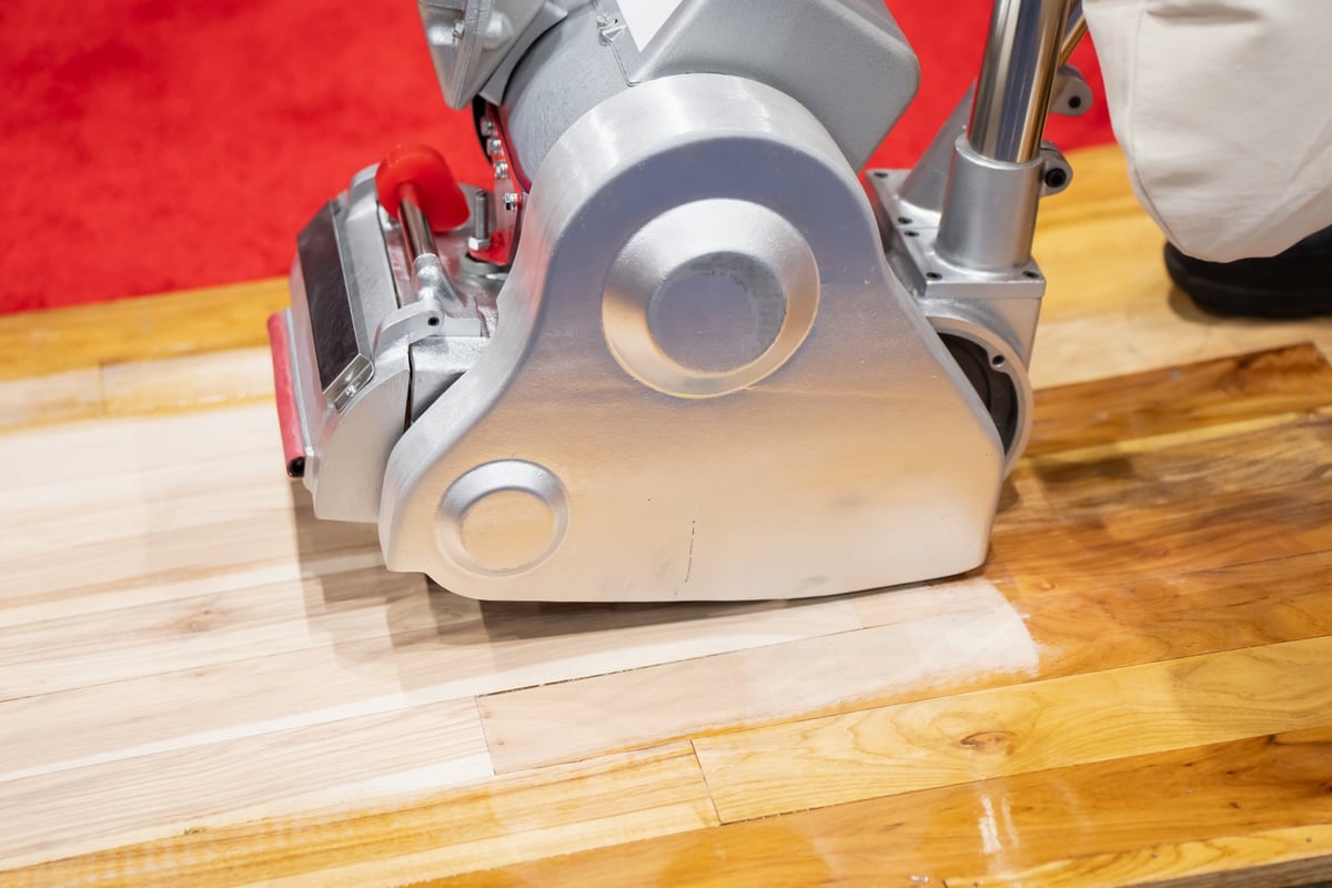 Floor sanding machine smoothing wooden boards during surface refinishing work