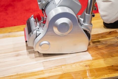 Floor sanding machine smoothing wooden boards during surface refinishing work