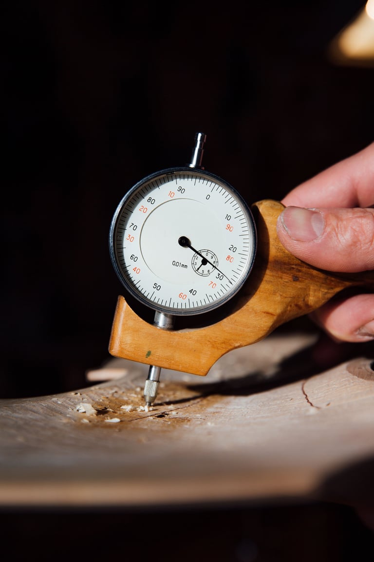 Master artisan luthier working on creation of violin. detailed work on wood with tools. analog mechanical thickness measuring device. artist hand measures the thickness of the future violin's scale.