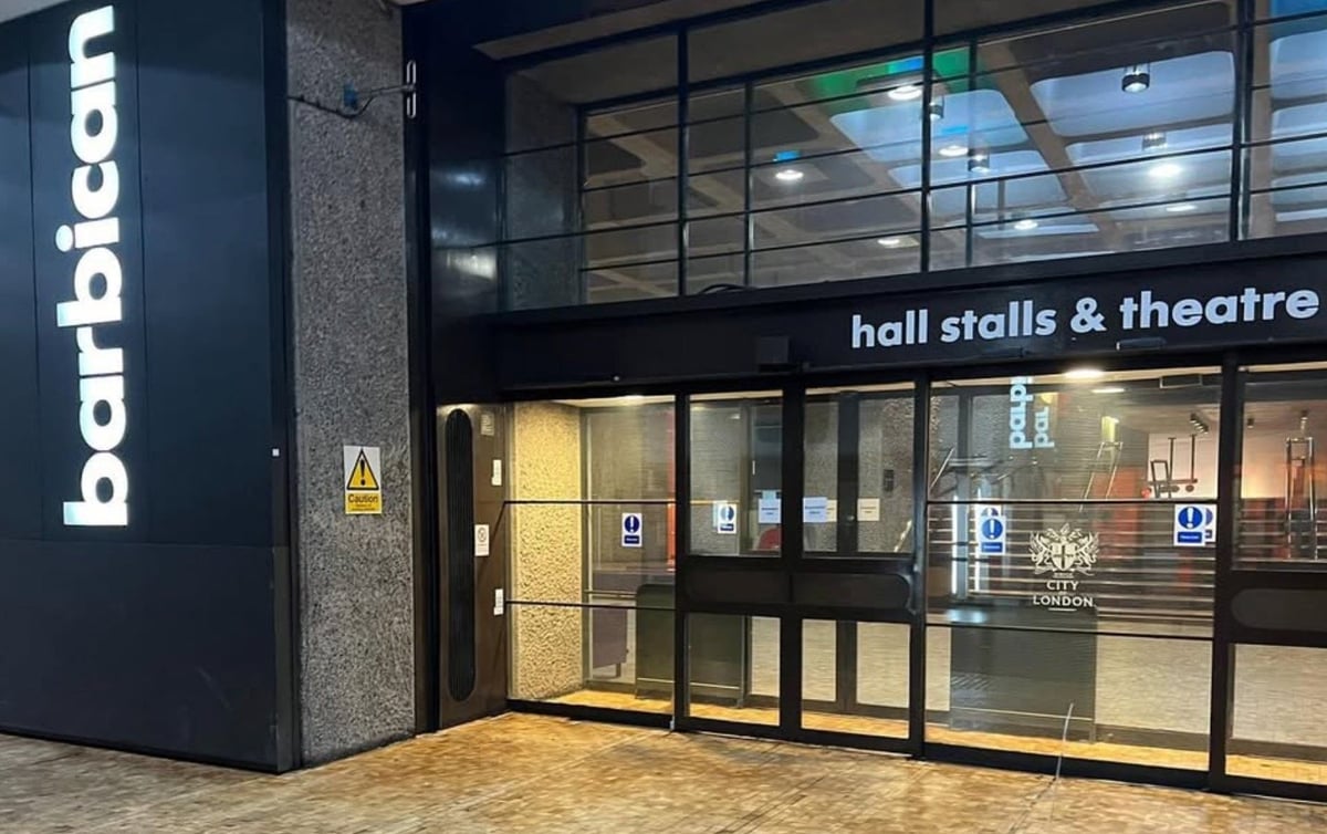 Barbican hall stalls and theatre entrance with glass doors and dark signage in modern corridor