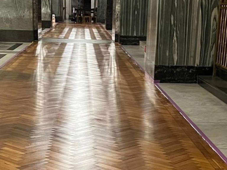 Bright hallway with polished herringbone wooden floor and sunlight streaming through, showing modern interior corridor