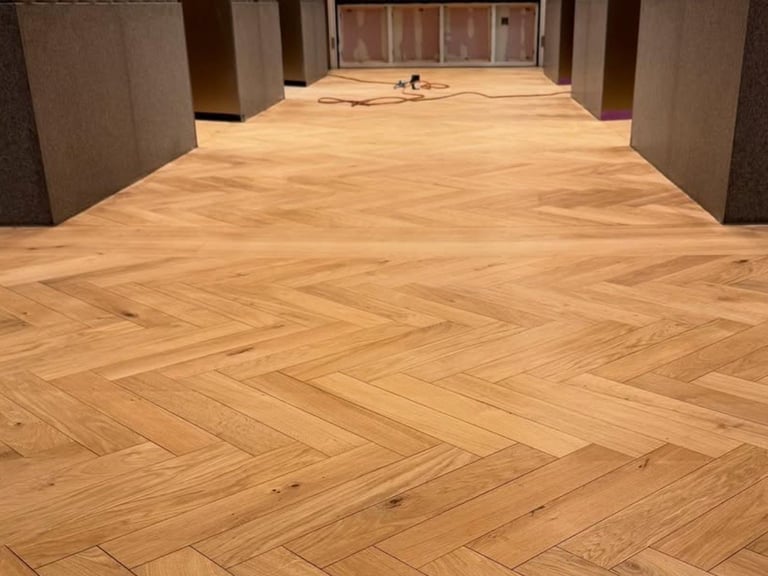 Interior hallway with herringbone pattern hardwood flooring and industrial support columns