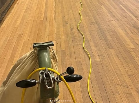 Overhead view of vintage bicycle with yellow handlebars on wooden floor, yellow cable visible