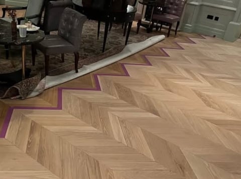 Herringbone wood flooring with purple accent inlays in a living room with furniture and area rug