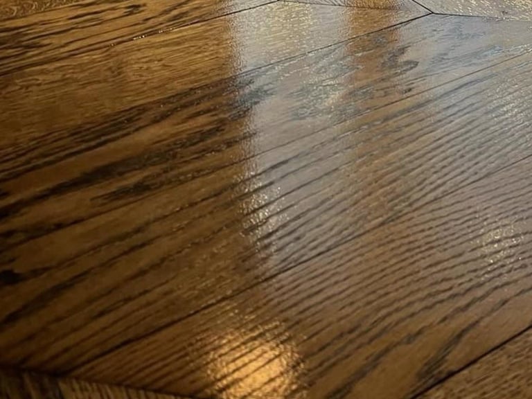 Close-up of wooden floor showing contrast between darker stained and lighter finished wood planks with wood grain detail