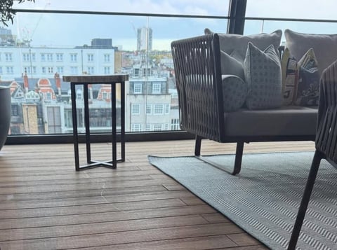Modern rooftop terrace with dark furniture and city skyline view through windows