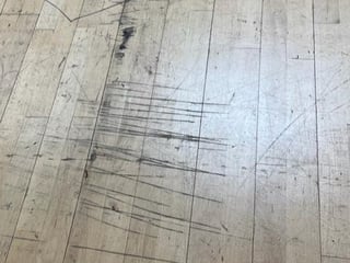Architectural blueprint or floor plan drawing overlaid on wooden flooring