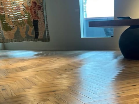 Bright studio space with wooden herringbone floors, exercise ball, wall art, and natural light from windows