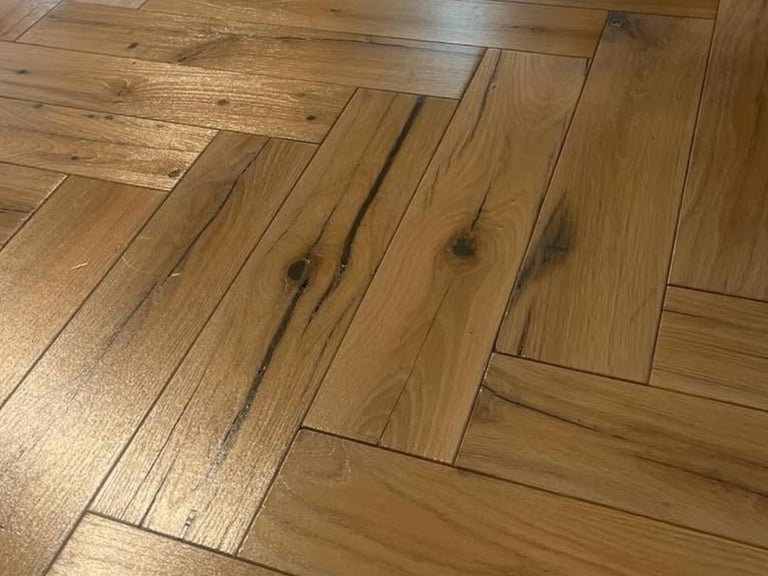 Close-up of herringbone pattern hardwood flooring with warm golden-brown tones and natural wood grain details