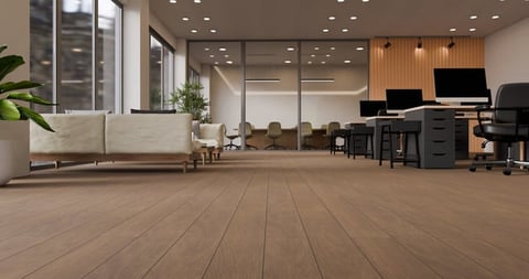 Modern open-plan office space with wooden flooring, seating area, computer workstations